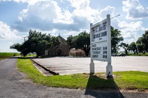 St. James Catholic Church with signage in a rural setting, captured under a bright sunny sky. jigsaw puzzle