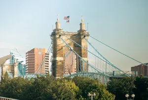Iconic John A. Roebling Suspension Bridge spanning the Ohio River with a cityscape backdrop. jigsaw puzzle