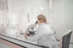 A scientist works with a microscope in a bright, modern lab setting, wearing a lab coat. jigsaw puzzle