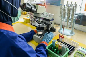 Technician in lab coat examining samples using a microscope in a modern laboratory setting. jigsaw puzzle