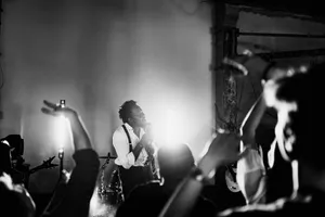 Energetic black and white photo of a singer performing on stage with a lively crowd. jigsaw puzzle