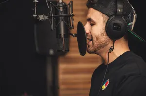 A young male musician singing in a professional recording studio with a microphone and headphones. jigsaw puzzle