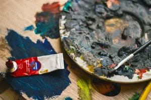 Close-up view of an artist's palette with mixed oil paints and a brush placed on a wooden surface. jigsaw puzzle