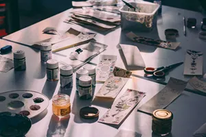 A creative workspace with paints, brushes, and decorative paper designs in a sunlit studio. jigsaw puzzle