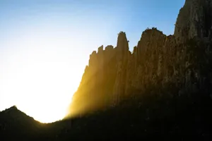 Sunlight beams through jagged mountain peaks at dawn. jigsaw puzzle