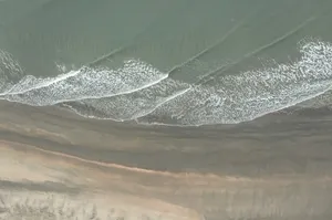 an aerial view of a sandy beach with waves jigsaw puzzle