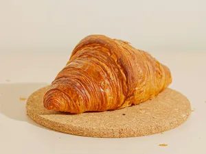 a croissant sitting on top of a cork coaster jigsaw puzzle