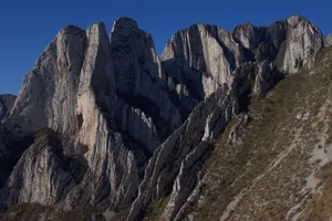 Explore a breathtaking mountain landscape showcasing rugged rock formations under a clear blue sky. jigsaw puzzle