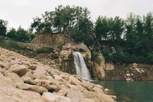 Beautiful waterfall cascading over rocks surrounded by lush greenery and trees. jigsaw puzzle