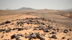 Vast desert scenery showcasing sandy dunes and rocky outcrops under a clear sky. jigsaw puzzle