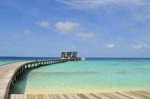 Beautiful tropical beach with a long wooden jetty stretching into the turquoise ocean in the Maldives. jigsaw puzzle
