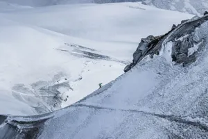 From above distant alpinist on snowy rough mountain slope against frozen spacious mountainous valley in daylight jigsaw puzzle