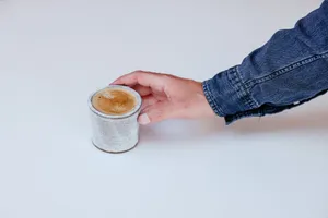 A cozy ceramic cappuccino cup being picked up on a white background. jigsaw puzzle
