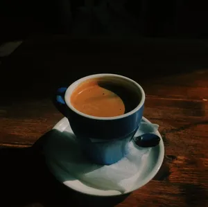 A warm cup of coffee in a blue mug on a wooden table, capturing a cozy cafe ambiance. jigsaw puzzle