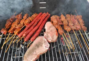 A variety of meats being grilled on a charcoal barbecue. jigsaw puzzle