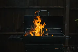 A close-up of an outdoor barbecue grill with blazing flames over charcoal, perfect for summer grilling. jigsaw puzzle