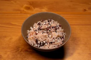 Appetizing bowl of traditional sticky rice mixed with beans and sesame seeds on a wooden surface. jigsaw puzzle