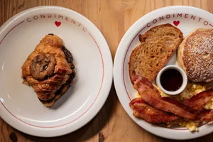 A delectable breakfast spread featuring a croissant and hearty bacon meal on styled plates. jigsaw puzzle