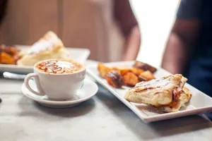Dining table with delicious grilled sandwich and sweet potato served near freshly brewed cappuccino jigsaw puzzle