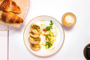 Top view of breakfast with croissants, a plate of eggs with parsley, and a cappuccino. jigsaw puzzle
