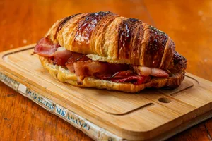 Delicious bacon-stuffed croissant served on a wooden cutting board, perfect for breakfast. jigsaw puzzle