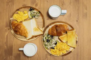 Delicious Japanese breakfast featuring eggs, toast, and milk on a wooden table setting. jigsaw puzzle