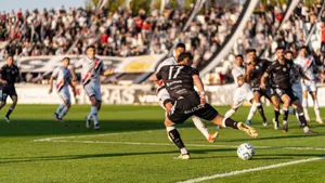 A dynamic football match with players in motion on a sunny day, witnessed by a packed stadium. jigsaw puzzle