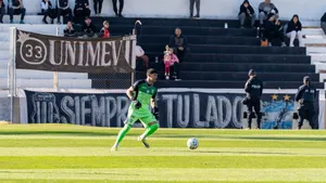 Soccer player in green uniform dribbling ball on field during a sunny day match. jigsaw puzzle