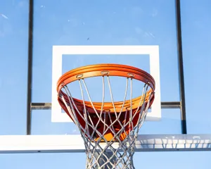 Close-up of an orange basketball hoop and net against a clear blue sky. jigsaw puzzle