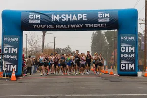 A group of runners reach the halfway mark in a marathon under an inflatable arch. jigsaw puzzle