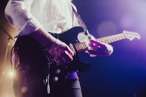 Close-up of a musician passionately playing an electric guitar under stage lights. jigsaw puzzle
