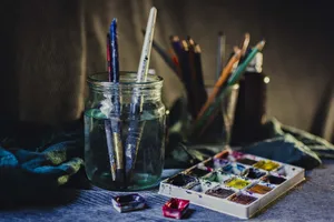 A creative still life of paintbrushes in a jar with watercolors and pencils, perfect for artistic inspiration. jigsaw puzzle