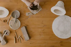 Hands sculpting clay in a pottery workshop, captured from above on a wooden table. jigsaw puzzle
