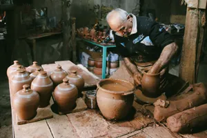Senior man handcrafting pottery jugs in a traditional workshop, showcasing skilled craftsmanship. jigsaw puzzle