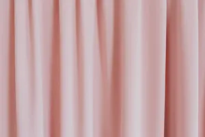 Close-up view of a soft pink curtain showcasing textured fabric folds. jigsaw puzzle