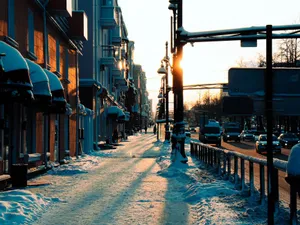 City street at sunset with snow-covered sidewalks and urban traffic, capturing winter ambiance. jigsaw puzzle