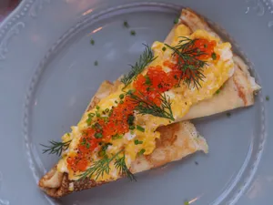 Scrumptious pancake topped with caviar, scrambled eggs, and fresh herbs on a decorative plate. jigsaw puzzle