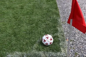 A close-up of a soccer ball near a red corner flag on a grass field, ideal for sports themes. jigsaw puzzle