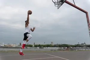 A man performs a high-flying basketball dunk on an outdoor court in Cologne, Germany. jigsaw puzzle