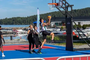 A group of young men playing basketball at an outdoor court near a marina. jigsaw puzzle