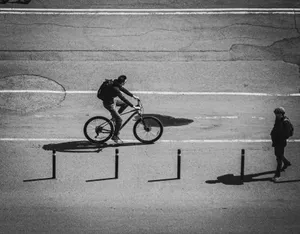 Monochrome image of a cyclist on city streets, highlighting urban life. jigsaw puzzle