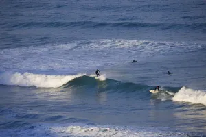 Surfers riding waves on a clear day at Watergate Bay in Cornwall, UK. jigsaw puzzle