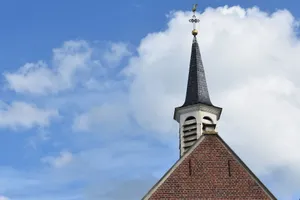 A classic chapel with a steeple, cross, and vibrant blue sky with clouds. jigsaw puzzle