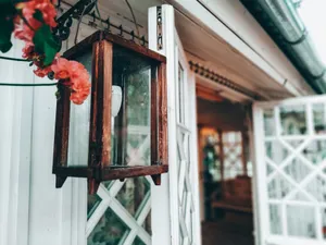 Close-up of a rustic wooden lantern with vibrant pink flowers at a house entrance. jigsaw puzzle