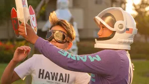 Two kids engage in imaginative play with astronaut gear and rocket toy outdoors. jigsaw puzzle