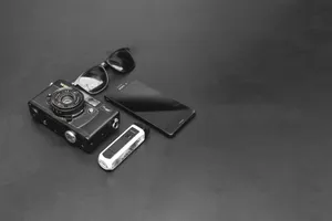 Monochrome flat lay featuring vintage camera, smartphone, and sunglasses on black background. jigsaw puzzle