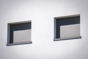 Close-up of a white wall showcasing two sunlit windows with minimalistic design. jigsaw puzzle