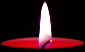 Detailed shot of a red wax candle with a bright flame against a dark background. jigsaw puzzle