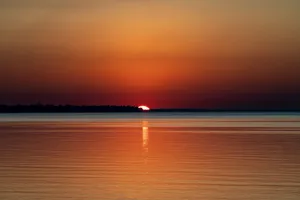A breathtaking sunset with vibrant colors reflecting on a tranquil water surface. jigsaw puzzle