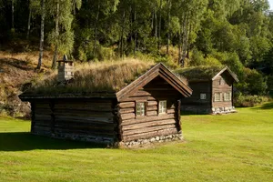 Two rustic log cabins with grass roofs in a field. jigsaw puzzle